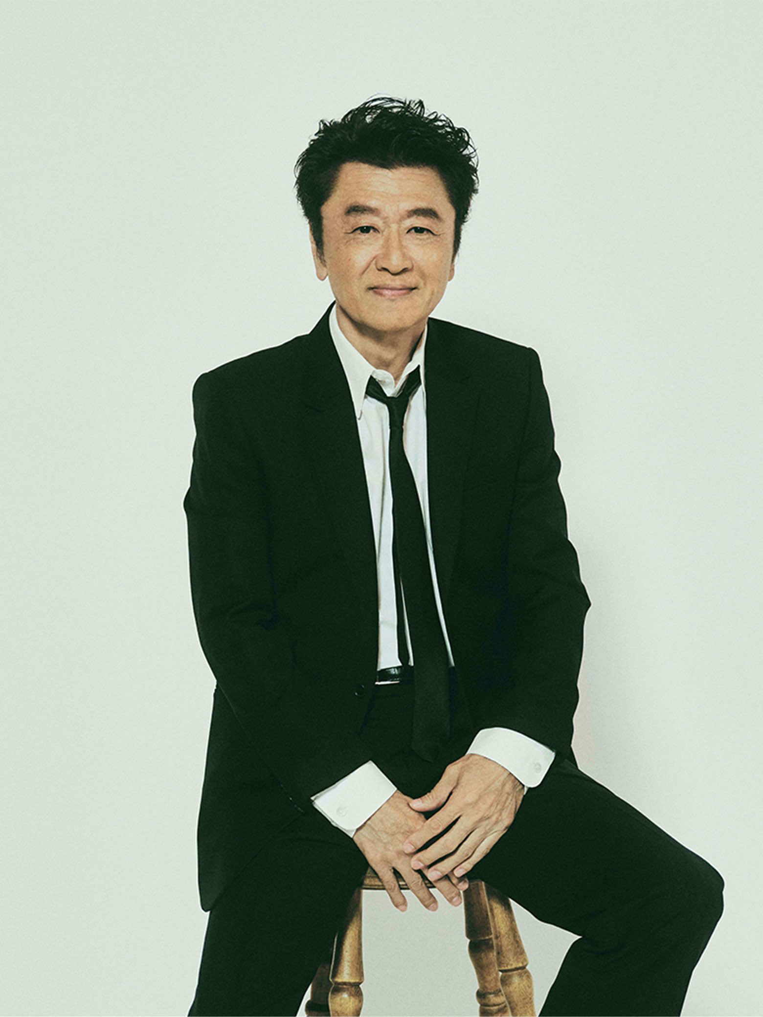 スーツ姿で椅子に座る桑田佳祐さん