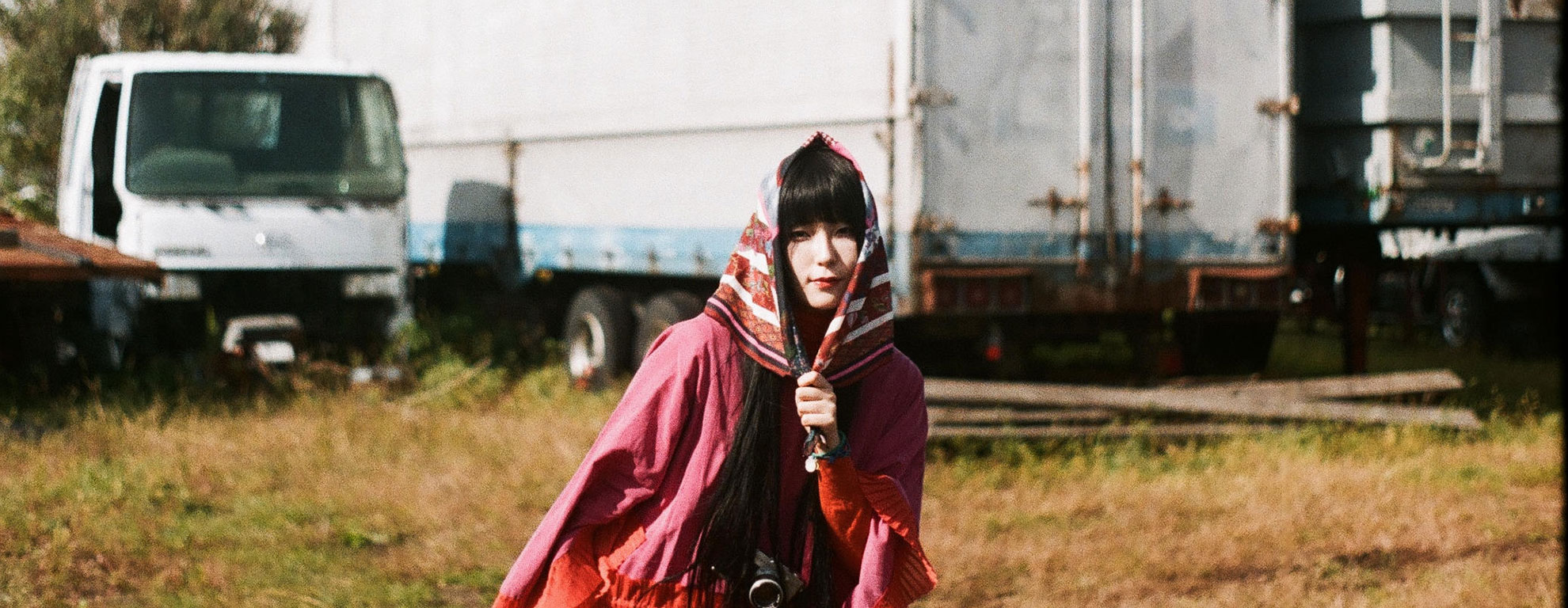 Daokoの公式プロフィール掲載写真。赤い衣装でこちらを見る姿