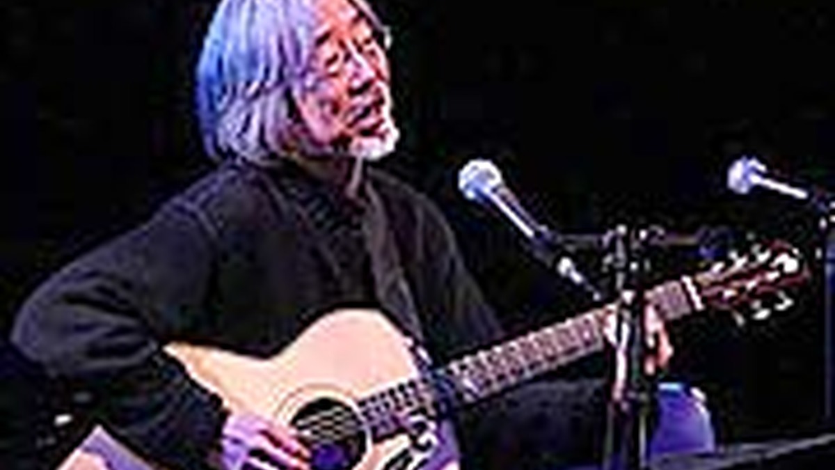 舞台でギターを弾く小室等