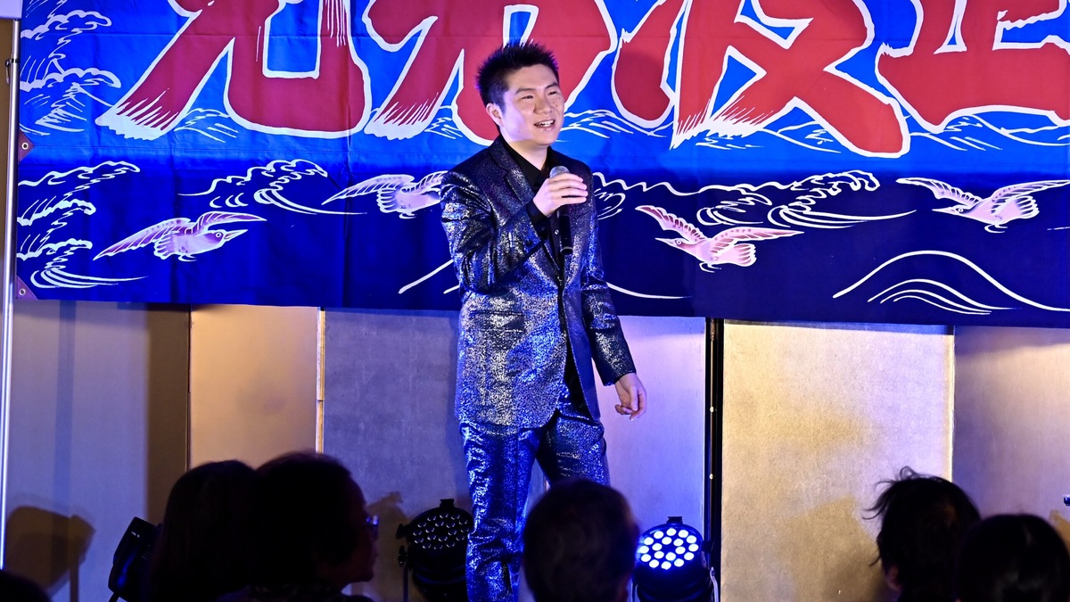 海を描いた幕の前で歌う一条貫太
