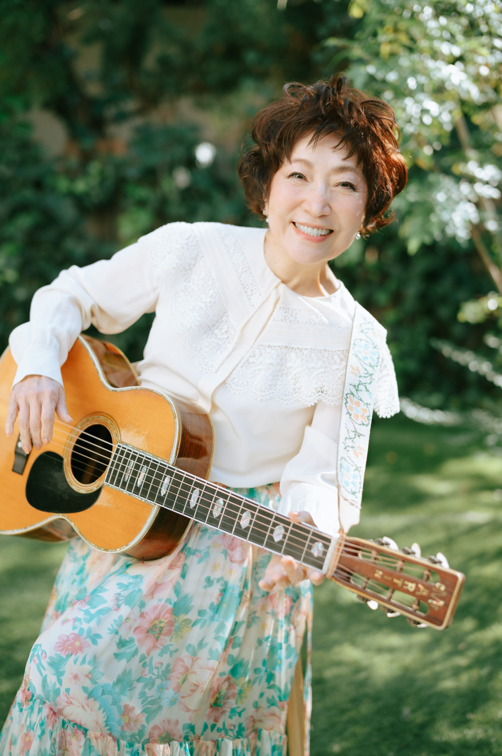 屋外でギターを抱えて微笑む森山良子