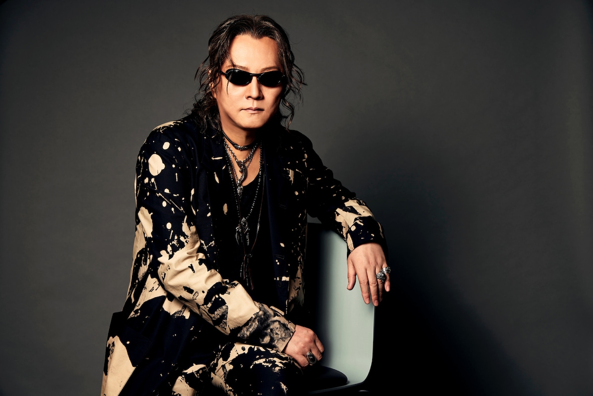 椅子に腰かける石井竜也