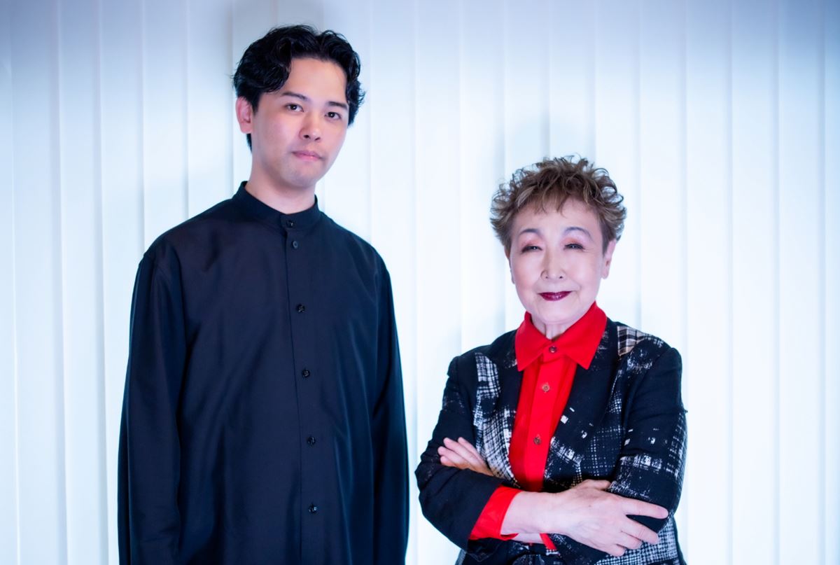 白いカーテンの前に並ぶ江﨑文武と加藤登紀子